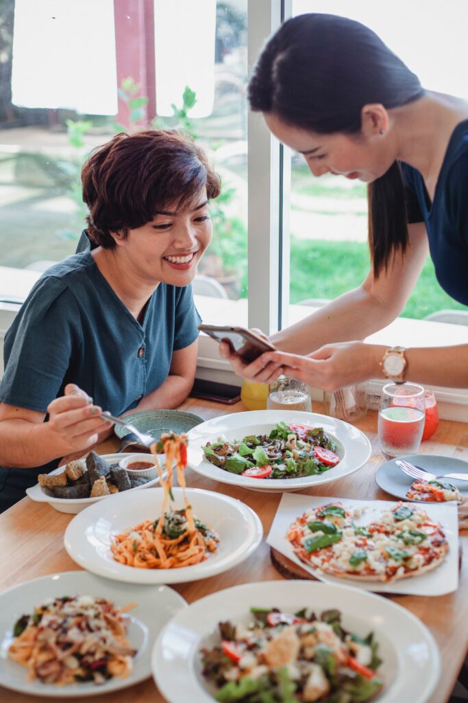 Women looking at phone during meal in sunny restaurant